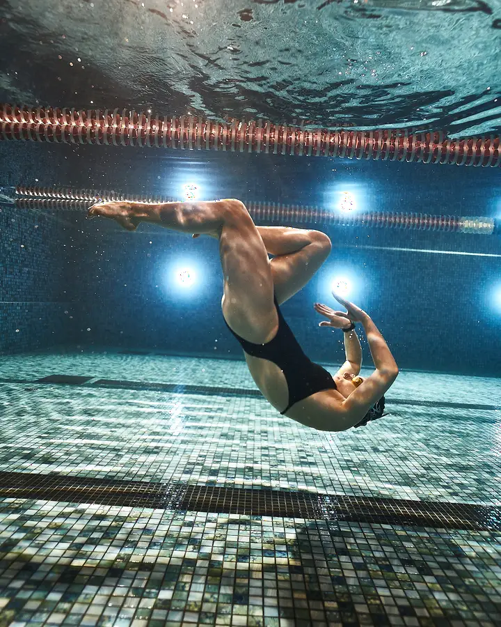 Synchronschwimmerin im kraftvollen Salto unter Wasser