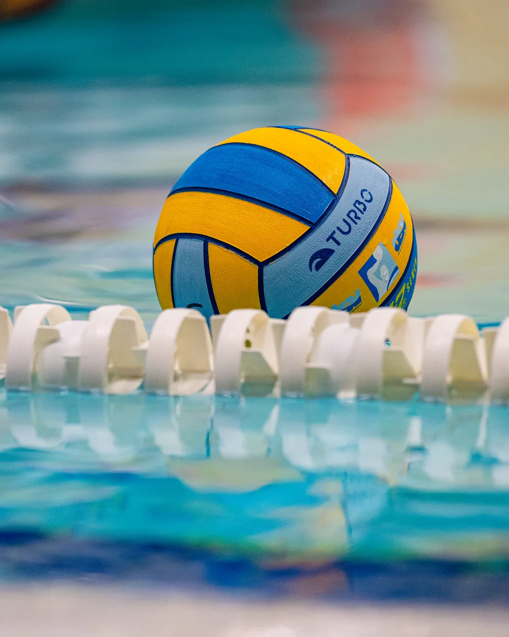 Gelb-blauer Wasserball auf der Bahnleine im Becken